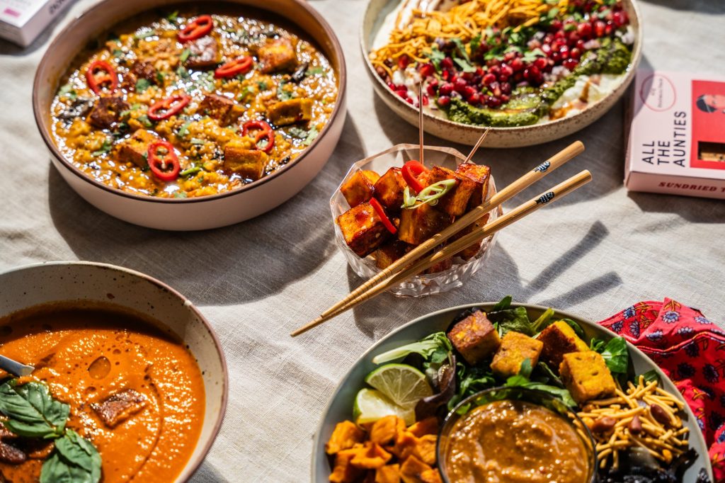 A spread of All The Aunties paneer dishes including curry, soup, salad and skewers on a table
